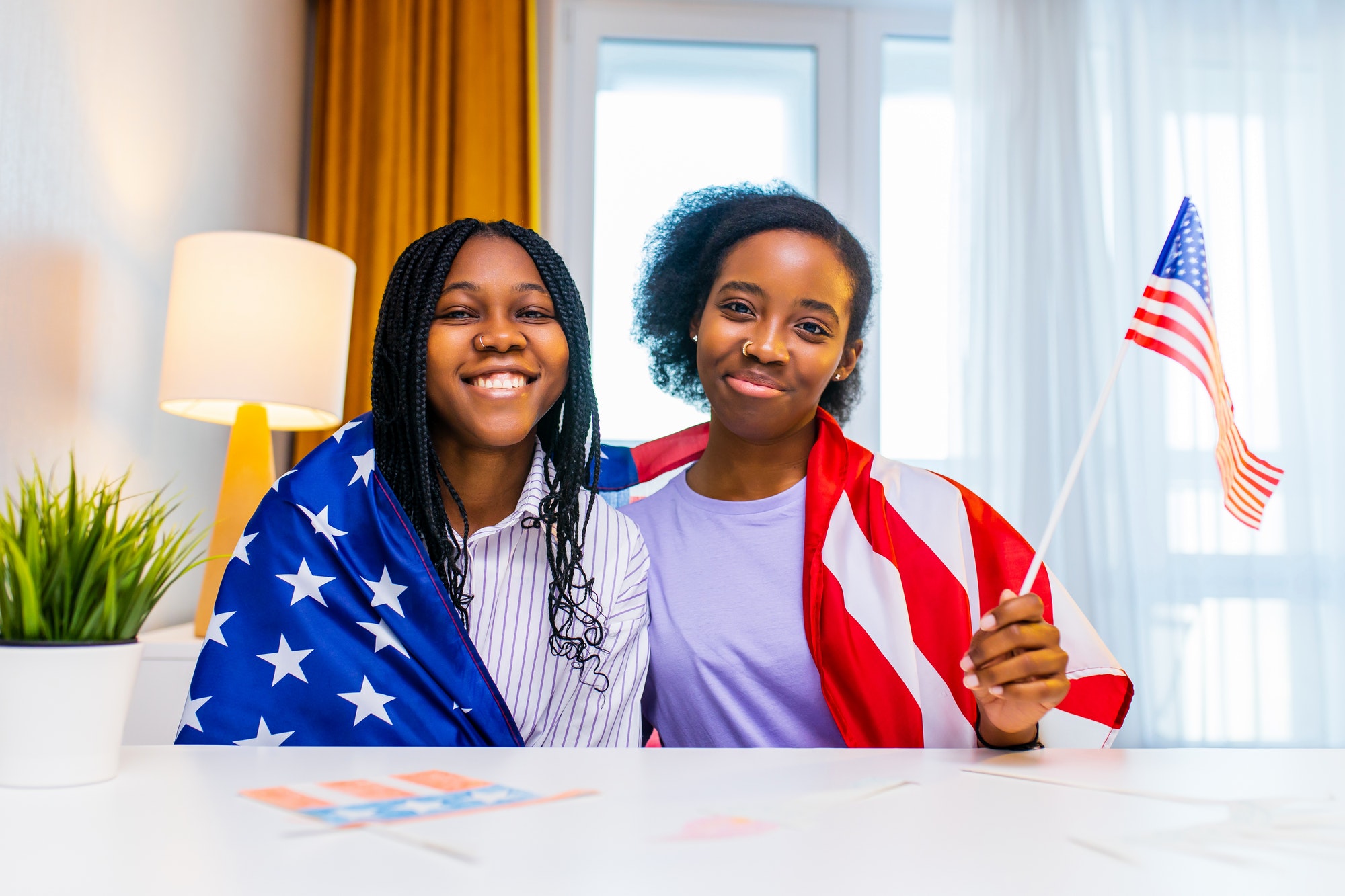 two happy african american sister celebrating usa independence day at home in cozy apartment
